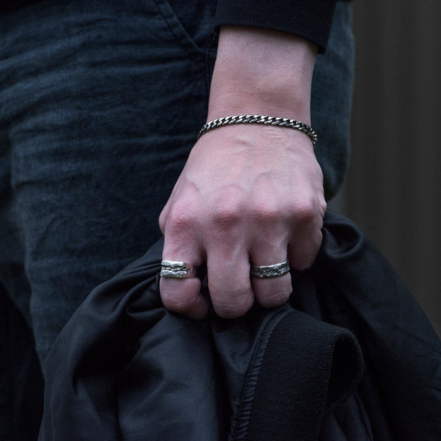 carved band silver ring on a finger