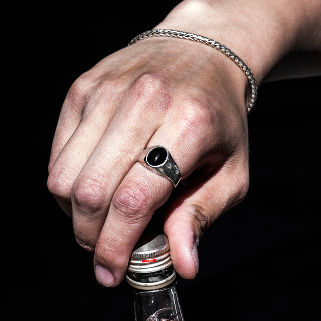 black gemstone signet ring on a finger